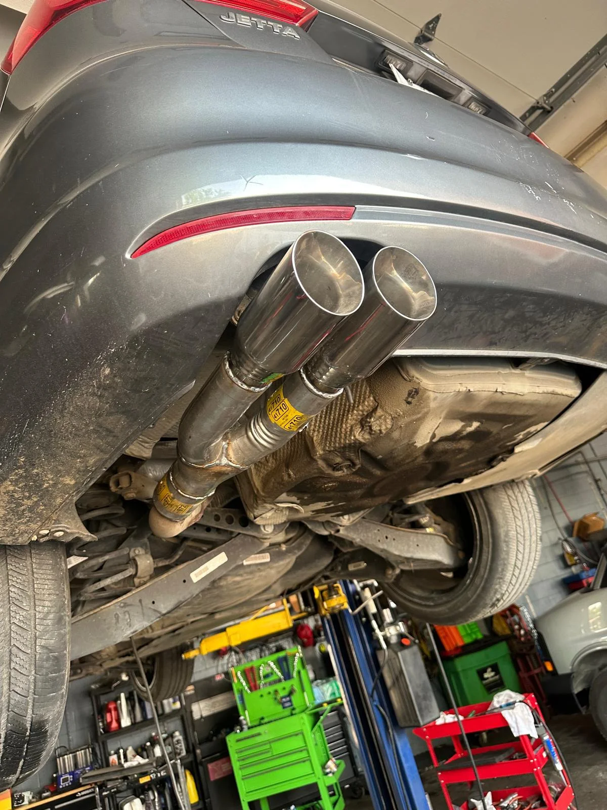 Finished dual polished exhaust tips on a gray Volkswagen Jetta